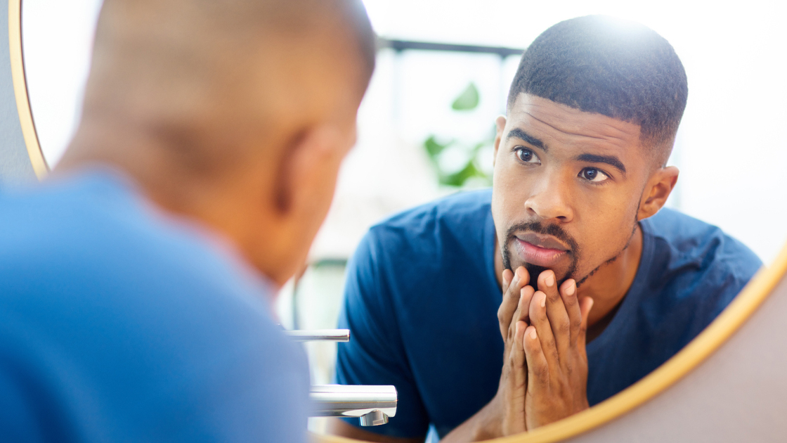 Shot of young man admiring his face in his bathroom mirror