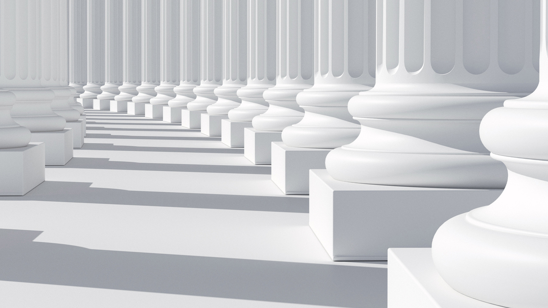 Row of columns aligned along a corridor, with white marble floor and shadow pattern. Detail of base with rounded shape. Abstract background of classic roman and greek colonnade. Digital image.