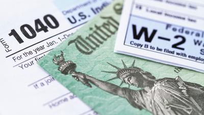 1040 income tax form and w-2 wage statement with a federal Treasury refund check. Closeup with selective focusing.