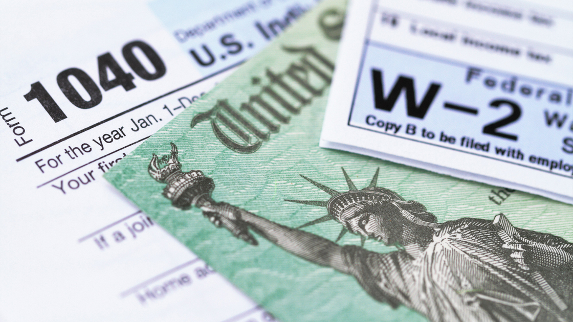 1040 income tax form and w-2 wage statement with a federal Treasury refund check. Closeup with selective focusing.
