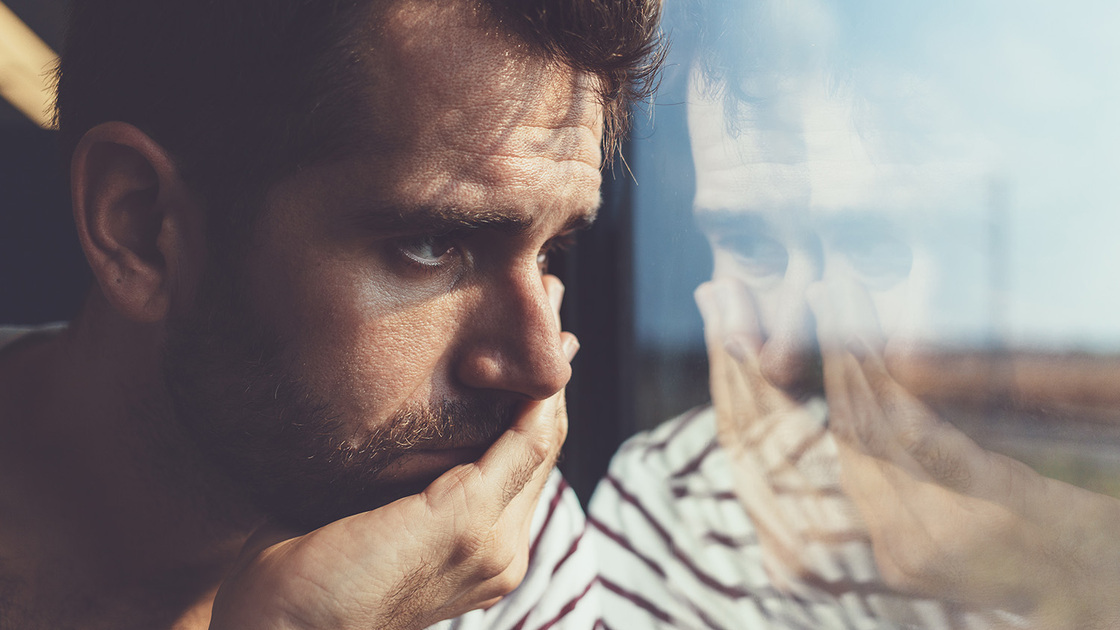 Sad young man looking through the window stock photo