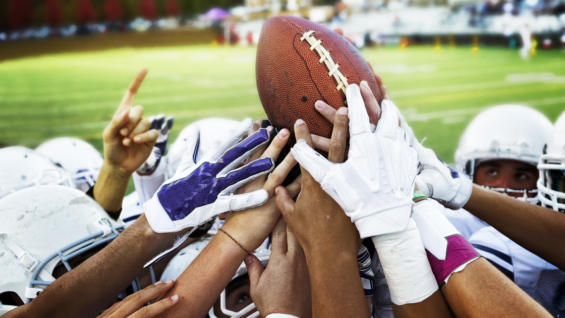 Football players holding up football.