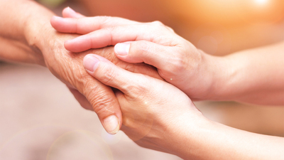 Caregiver, carer hand holding elder hand in hospice care. Philanthropy kindness to disabled concept.