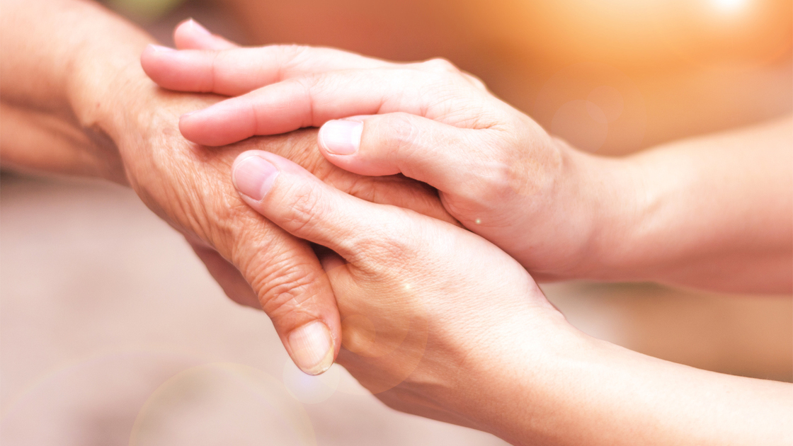 Caregiver, carer hand holding elder hand in hospice care. Philanthropy kindness to disabled concept.