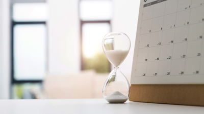 Calendar and hourglass on the table.