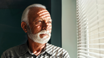 Pensive mature man looking through window at doctor's office.