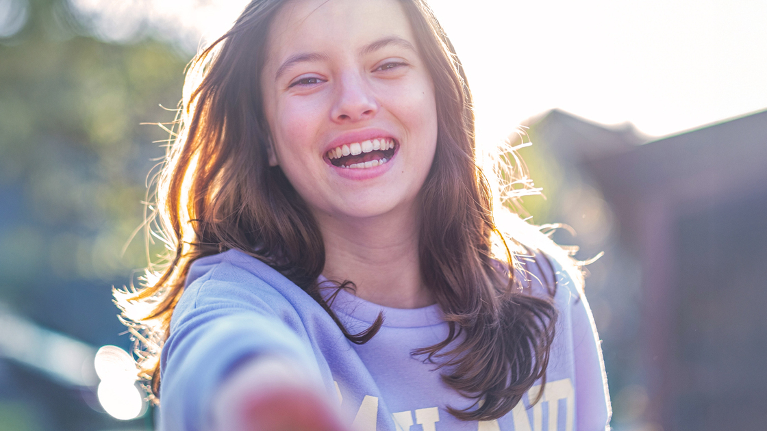 a beautiful teenage girl runs towards the camera outside